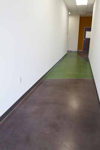 A hallway that has purple and green stained concrete floors.